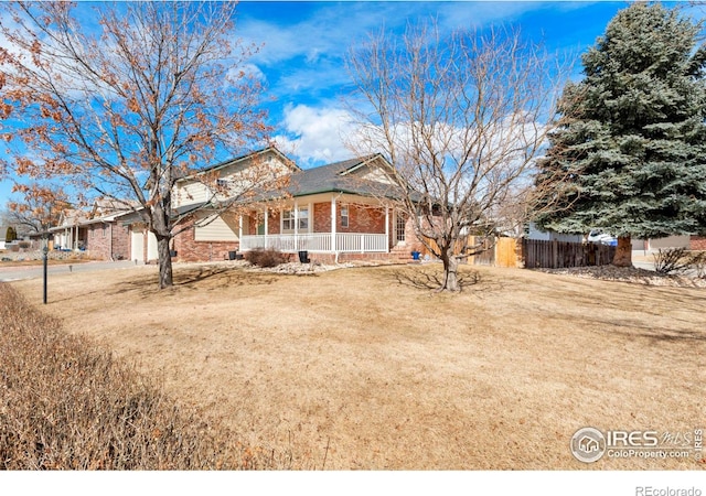 view of front of property with a garage, brick siding, fence, a porch, and a front yard