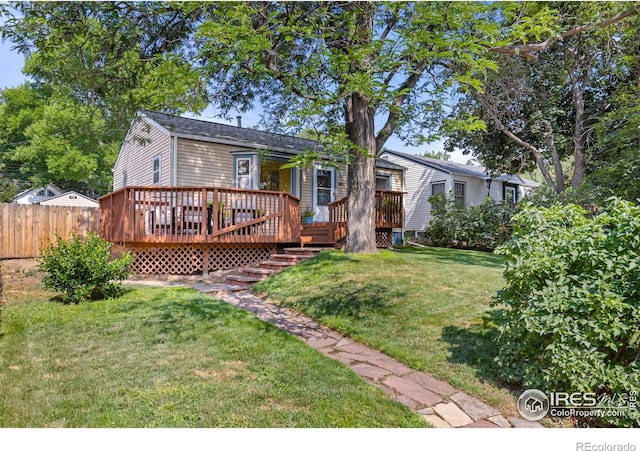 rear view of house with fence, a lawn, and a wooden deck