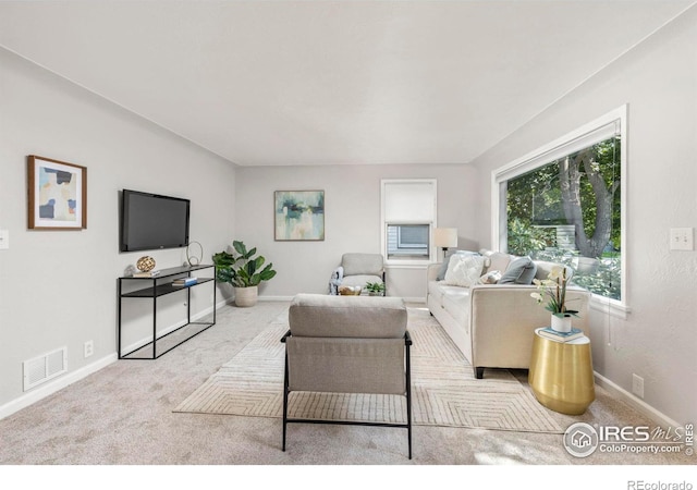 living room with light colored carpet, visible vents, and baseboards