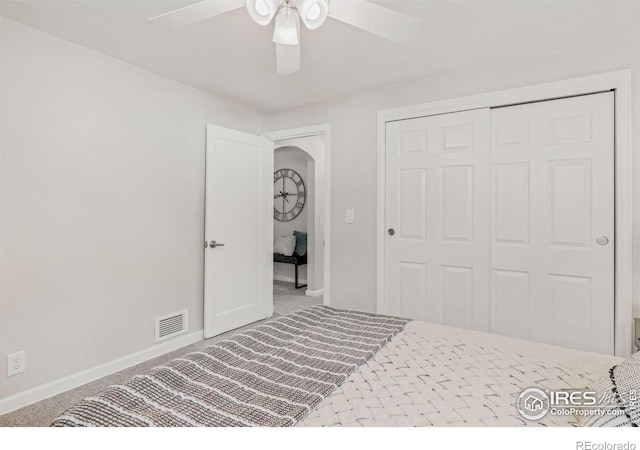 bedroom with a closet, visible vents, light carpet, ceiling fan, and baseboards