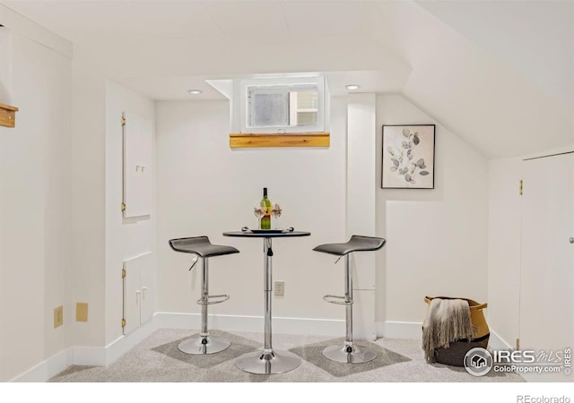 interior space featuring lofted ceiling, light colored carpet, and baseboards