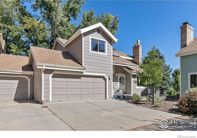 view of front of home featuring a shingled roof, concrete driveway, and a chimney