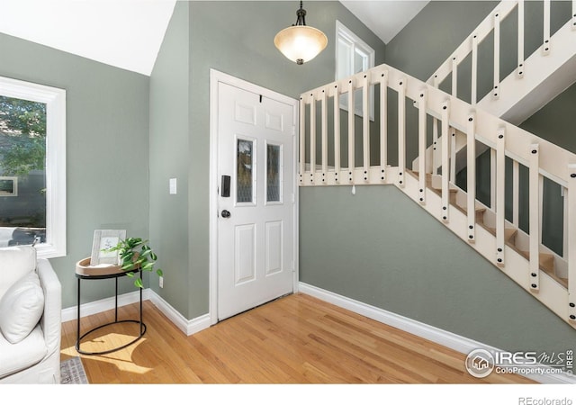 foyer with baseboards, stairway, and wood finished floors