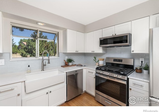 kitchen featuring light countertops, appliances with stainless steel finishes, a sink, and white cabinets