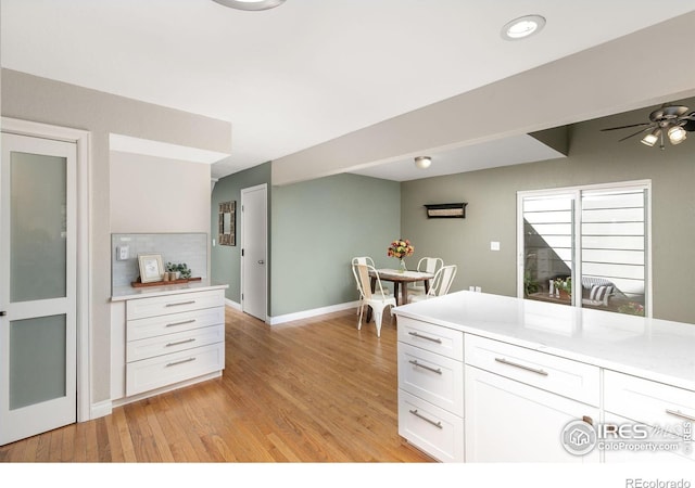 kitchen featuring a ceiling fan, white cabinets, light countertops, and light wood-style flooring