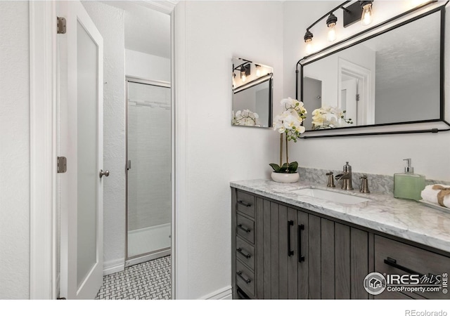 full bath with vanity, baseboards, and an enclosed shower