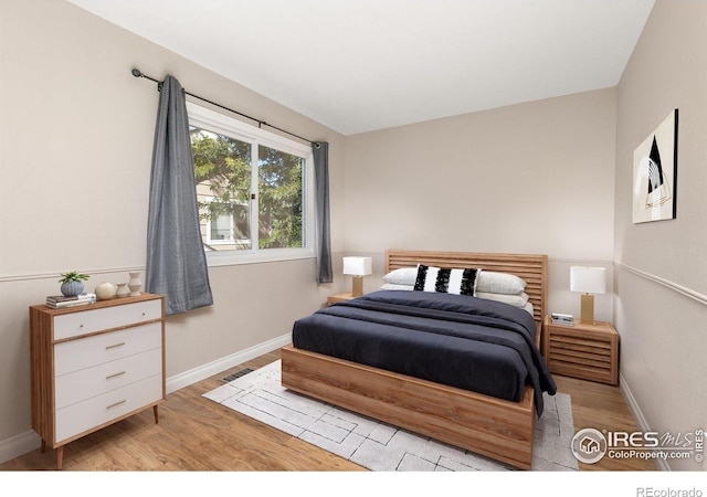 bedroom featuring baseboards, visible vents, and light wood finished floors