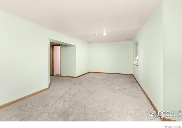 unfurnished room with light carpet and baseboards