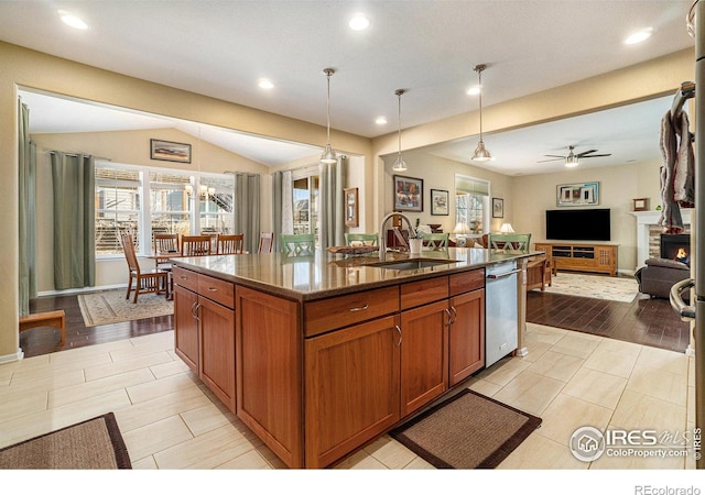 kitchen featuring brown cabinetry, open floor plan, a kitchen island with sink, pendant lighting, and stainless steel dishwasher