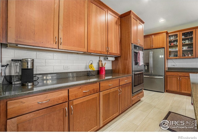 kitchen with brown cabinets, recessed lighting, backsplash, appliances with stainless steel finishes, and glass insert cabinets