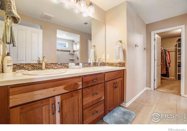 bathroom featuring tiled shower, a sink, a spacious closet, and decorative backsplash