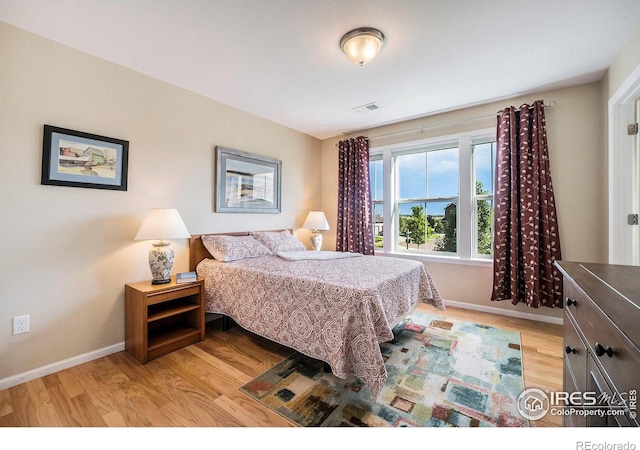 bedroom with visible vents, light wood-style flooring, and baseboards