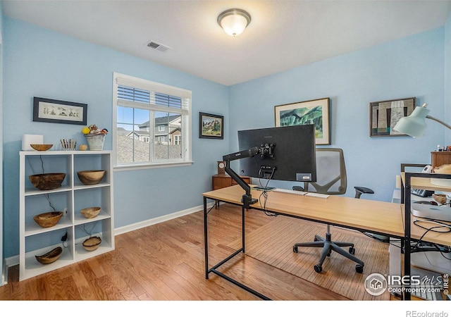 office space featuring baseboards, visible vents, and wood finished floors