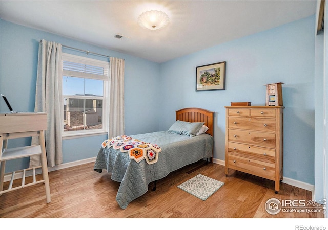 bedroom with visible vents, baseboards, and wood finished floors