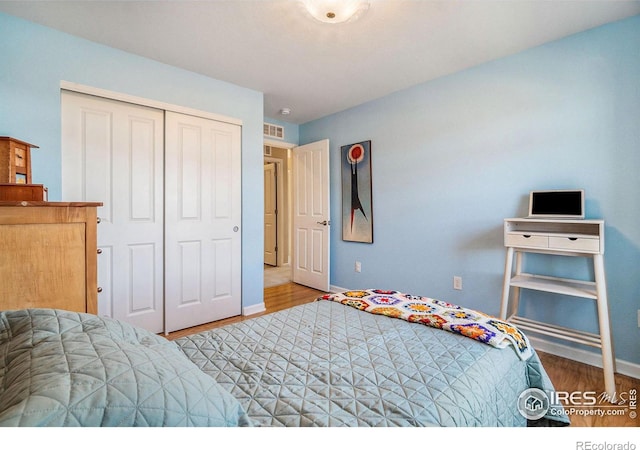 bedroom featuring light wood finished floors, a closet, visible vents, and baseboards