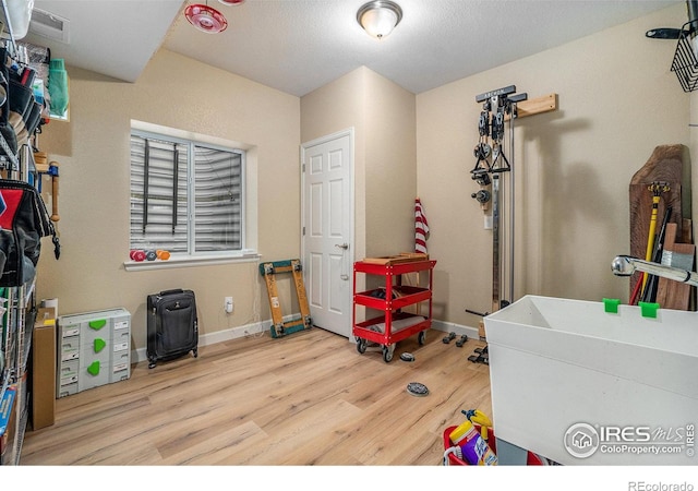 rec room with a sink, wood finished floors, visible vents, and baseboards