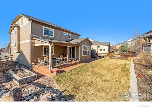 rear view of house featuring a patio, a lawn, fence, and board and batten siding