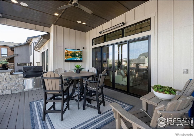 deck featuring exterior kitchen, outdoor dining area, and a ceiling fan