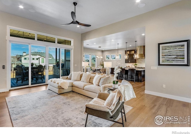 living area with light wood-type flooring, ceiling fan, baseboards, and recessed lighting