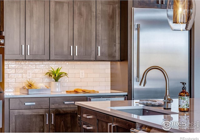 kitchen with tasteful backsplash, dark brown cabinets, and a sink