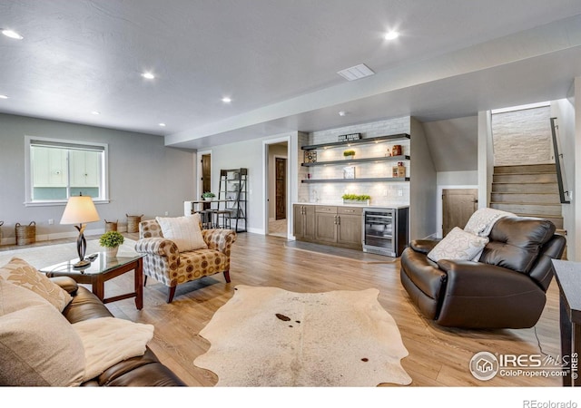 living area featuring wine cooler, recessed lighting, stairway, a bar, and light wood-type flooring