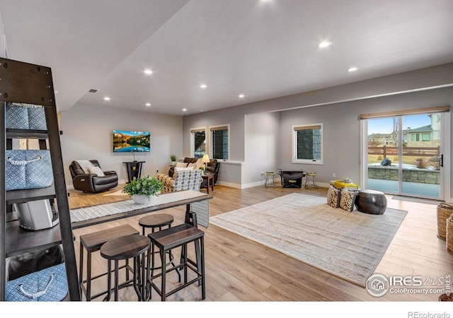 kitchen with a breakfast bar, light wood finished floors, open floor plan, and recessed lighting