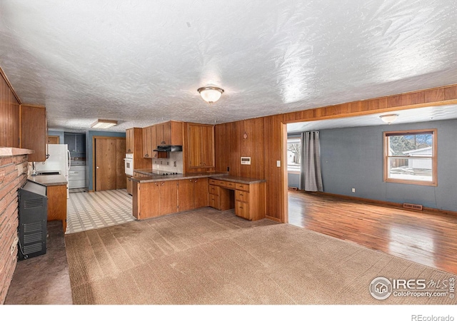 kitchen featuring light carpet, visible vents, open floor plan, brown cabinets, and white oven