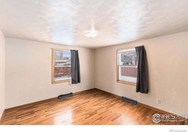 unfurnished room with light wood-style floors, visible vents, and baseboards