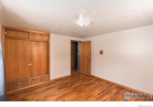 unfurnished bedroom with a closet, baseboards, and wood finished floors