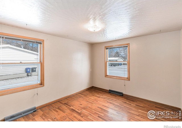 spare room with a textured ceiling, light wood finished floors, visible vents, and baseboards