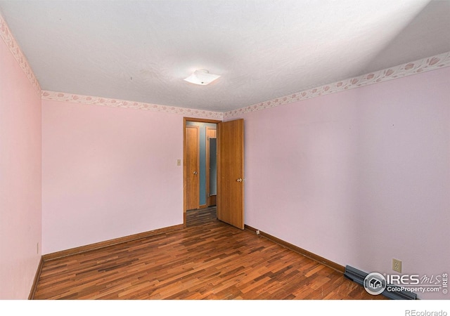 spare room with dark wood finished floors and baseboards