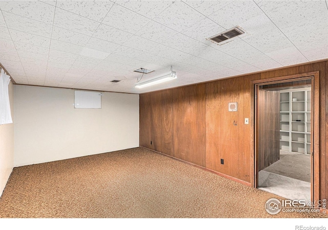 finished basement featuring carpet, visible vents, and wooden walls