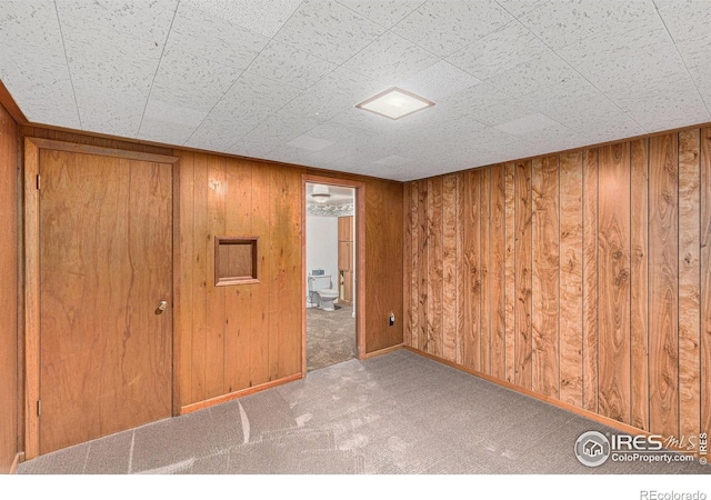 empty room with light carpet and wood walls