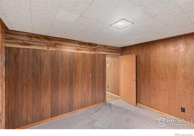 unfurnished room with light carpet and wood walls