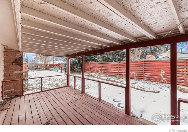 snow covered deck with a fenced backyard