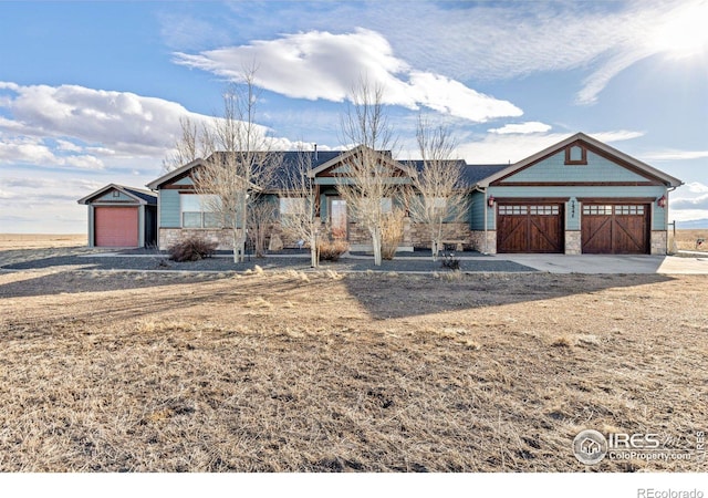 view of front of home featuring stone siding and concrete driveway