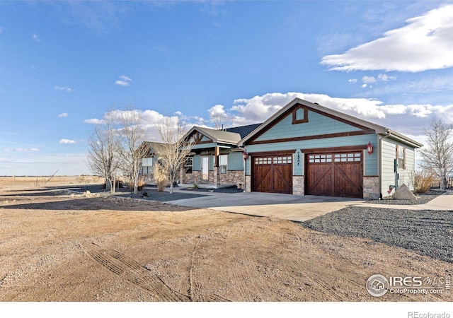 view of front of home with driveway, stone siding, and a garage