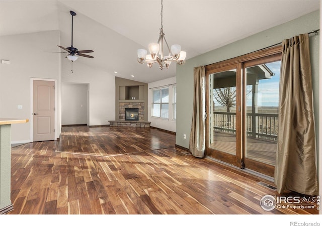 unfurnished living room with dark wood-style floors, a stone fireplace, vaulted ceiling, and visible vents