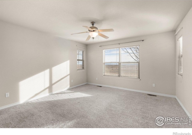 unfurnished room featuring ceiling fan, carpet flooring, visible vents, and baseboards