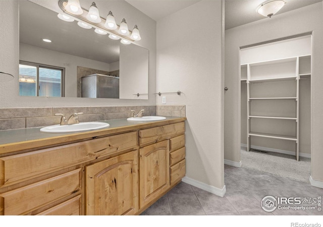 full bathroom featuring a stall shower, a sink, a walk in closet, and tile patterned floors