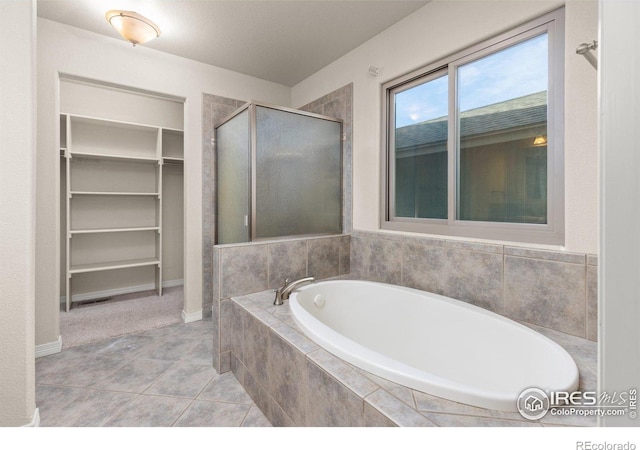 bathroom featuring a garden tub, a shower stall, a spacious closet, and tile patterned flooring