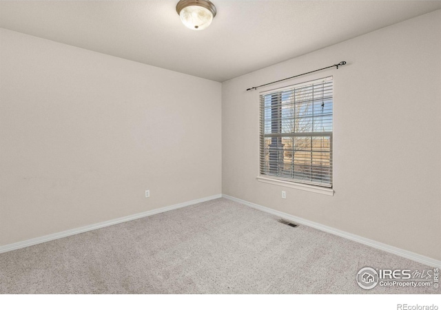 carpeted spare room featuring baseboards and visible vents