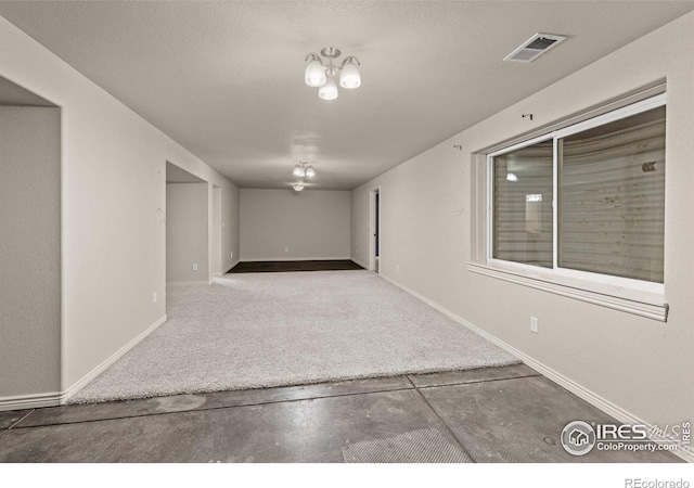 unfurnished room featuring visible vents, concrete floors, a textured ceiling, and baseboards