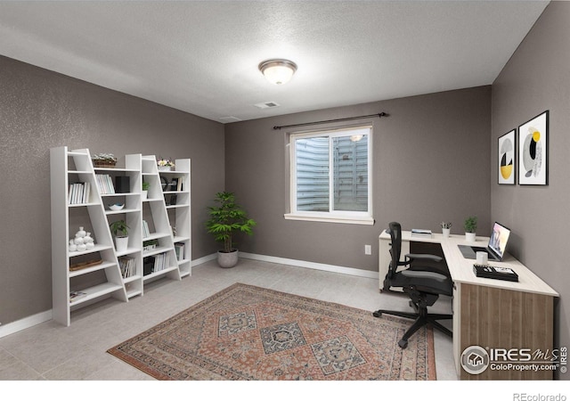 office space featuring light tile patterned floors, visible vents, baseboards, and a textured ceiling