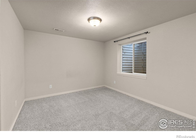 carpeted empty room featuring a textured ceiling, visible vents, and baseboards