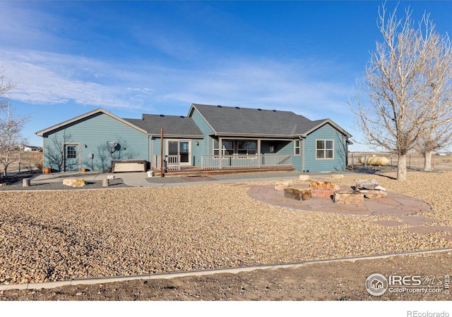 back of house with a hot tub, a patio area, a fire pit, and a deck