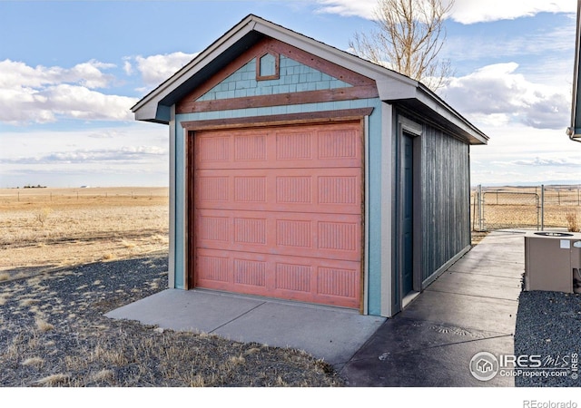 detached garage with fence and a rural view