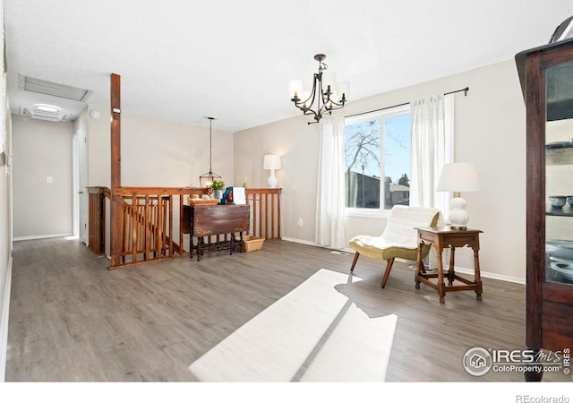 living area with baseboards, a notable chandelier, an upstairs landing, and wood finished floors