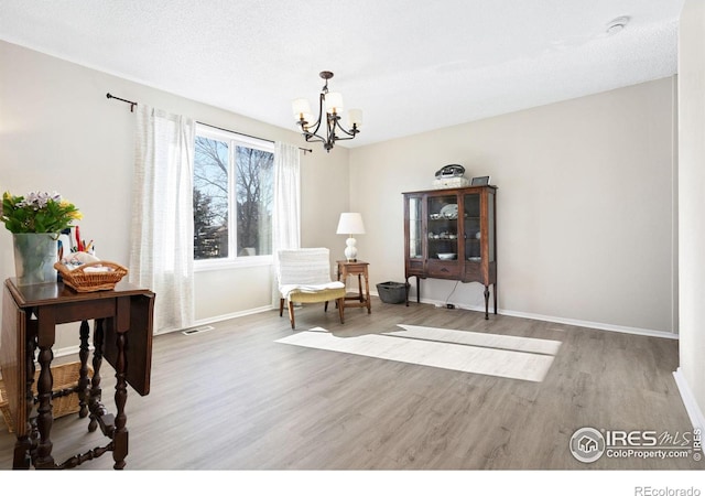 sitting room featuring an inviting chandelier, baseboards, visible vents, and wood finished floors