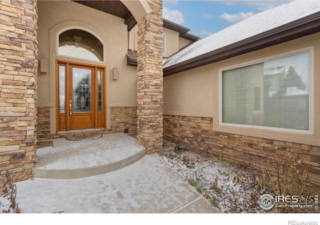 view of exterior entry featuring stone siding and stucco siding